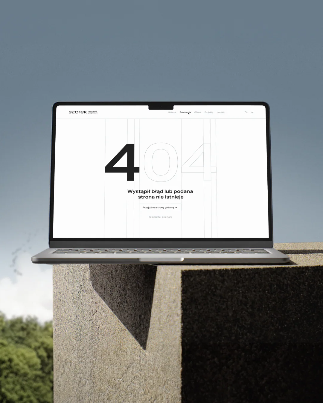 Design der 404-Fehlerseite der SZOREK-Website auf einem Laptop auf einem Betonblock